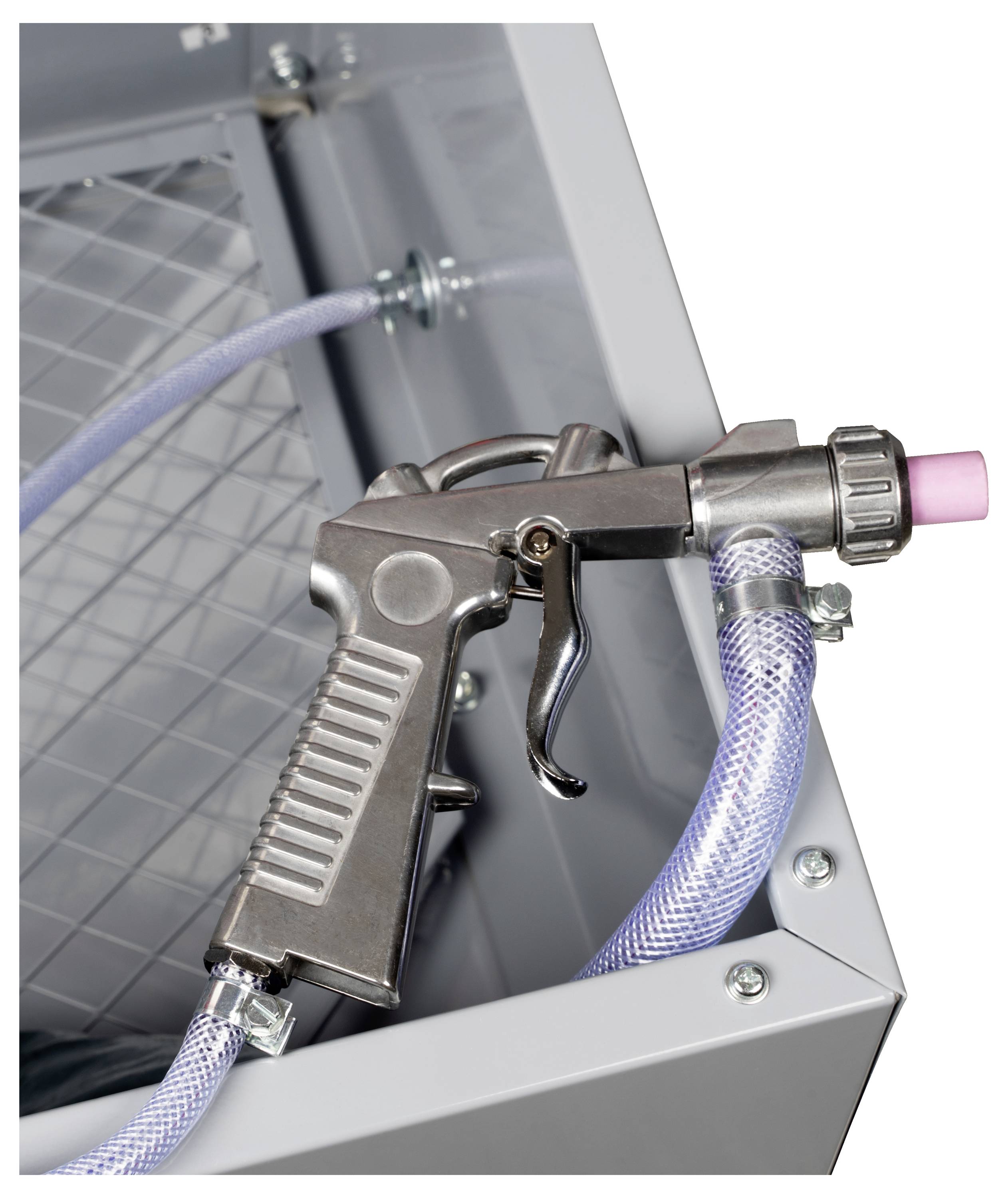 Eine Nahaufnahme einer Metallblastpistole mit einem strukturierten Griff, der an einen transparenten, geflochtenen Schlauch angeschlossen ist. Die Pistole ist auf einer Metalloberfläche montiert.