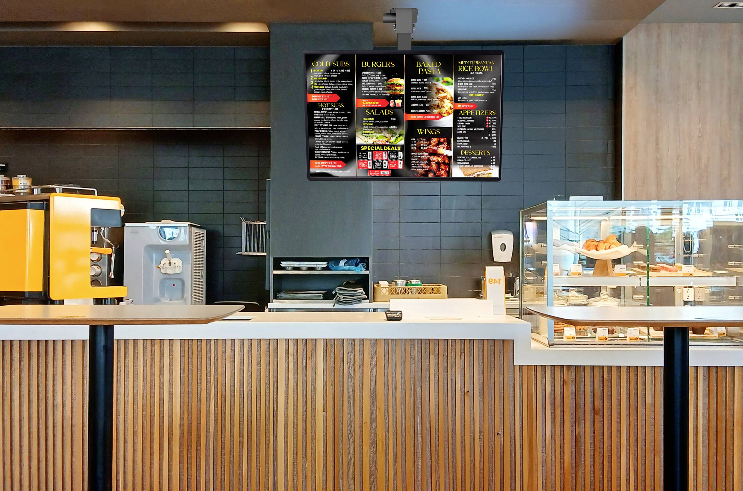 Eine moderne Café-Theke mit einer Vitrine für Gebäck, einer Kaffeemaschine und digitalen Menübildschirmen über der Theke, die verschiedene Speisen- und Getränkeangebote anzeigen.