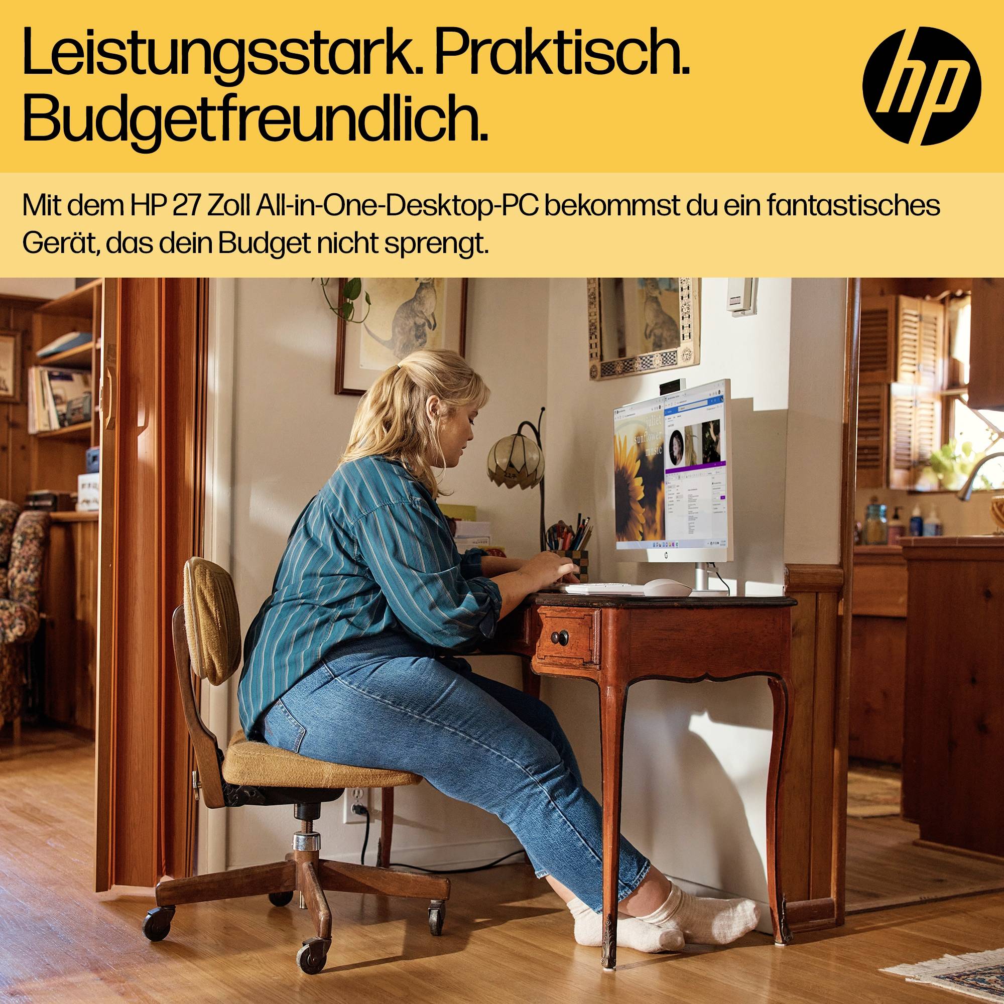 Eine Person sitzt am Schreibtisch vor einem All-in-One-Desktop-PC und arbeitet. Werbetext im Bild: 'Leistungsstark. Praktisch. Budgetfreundlich.'