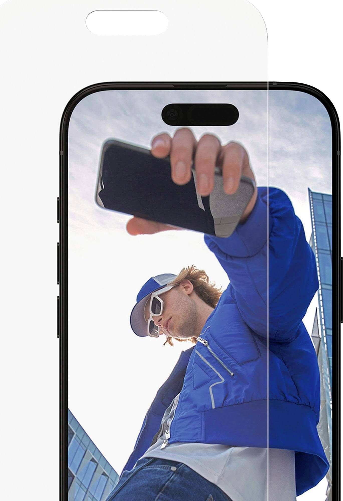 Eine Person in einer blauen Jacke und Sonnenbrille hält ein Smartphone in die Höhe, mit einem modernen Gebäude und blauem Himmel im Hintergrund.