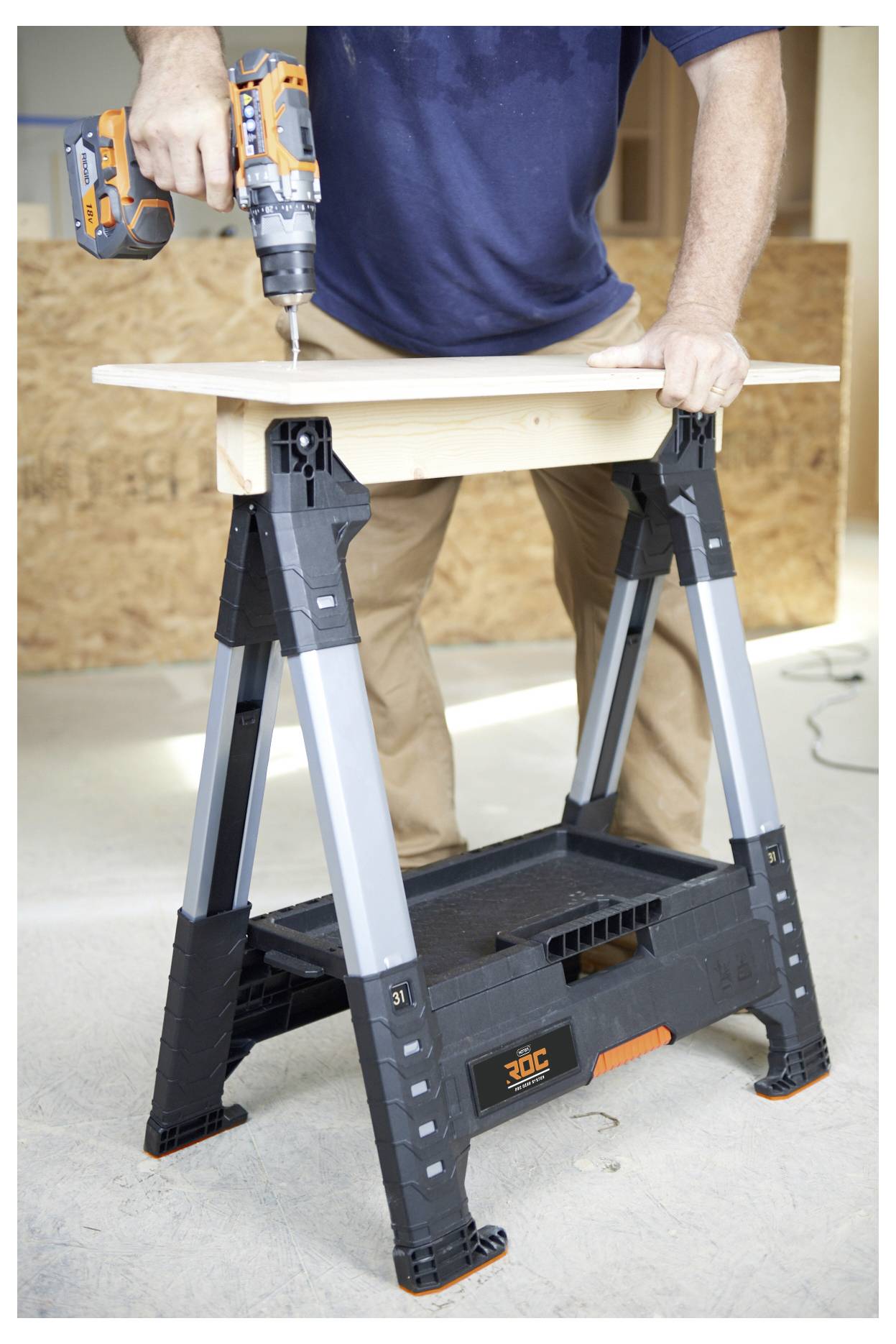 Person, der eine Bohrmaschine auf einem Holzbrett verwendet, das von einer Werkbank in einer Werkstattumgebung gestützt wird.