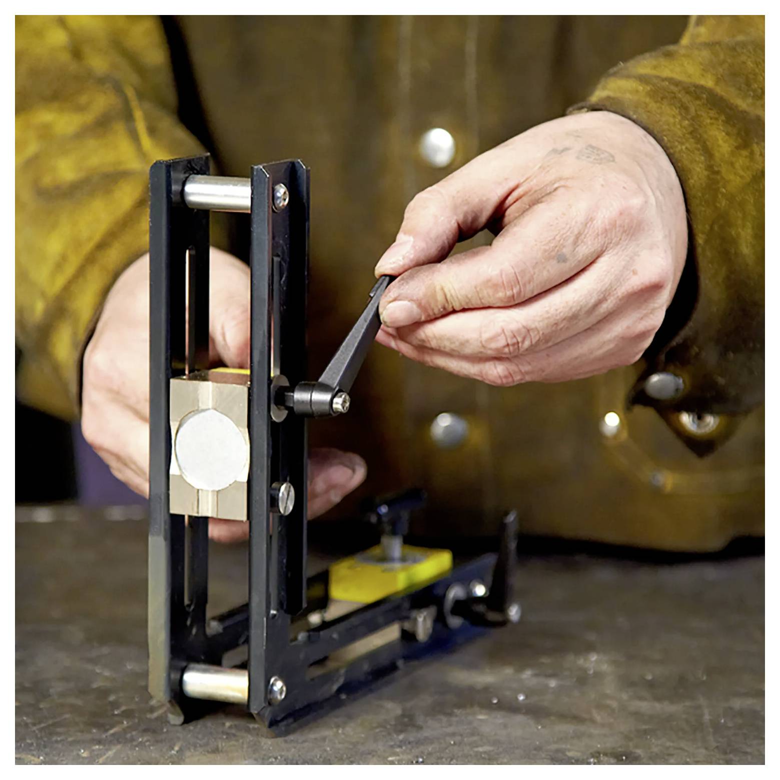 Eine Person, die ein Metalltool auf einer Werkbank justiert und sich mit sorgfältigen Handbewegungen auf Präzision konzentriert.