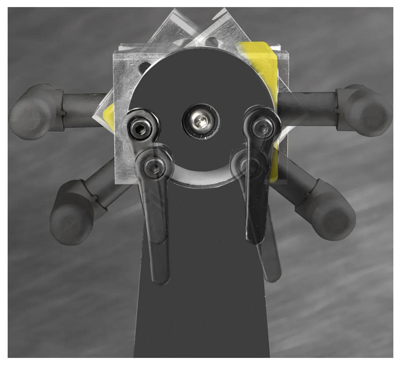 Eine mechanische Vorrichtung weist mehrere vorstehende Hebel und eine zentrale kreisförmige Komponente mit Schrauben auf, vor einem unscharfen grauen Hintergrund.