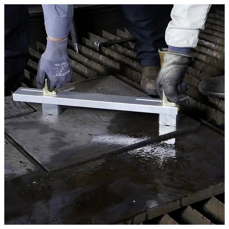 Zwei Arbeiter benutzen ein Metallwerkzeug, um schwere Stahlplatten zu justieren und bereiten diese für das Schneiden oder Schweißen in einer industriellen Umgebung vor.