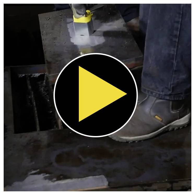 Wasserstrahlschneiden eines Metallblechs, mit Fokus auf der Düse, die Wasser und Schleifmaterial ausspritzt. Ein Video-Play-Button überlagert das Bild.