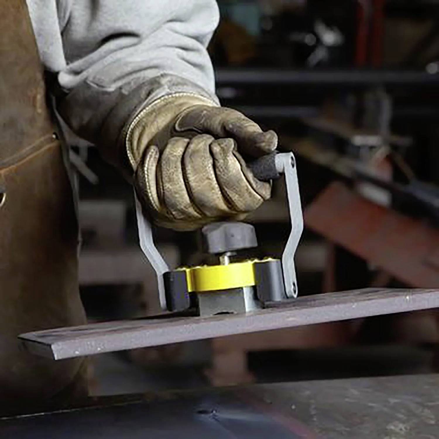 Ein Arbeiter mit Handschuhen verwendet einen magnetischen Heber, um eine Metallplatte in einer industriellen Umgebung zu bewegen.