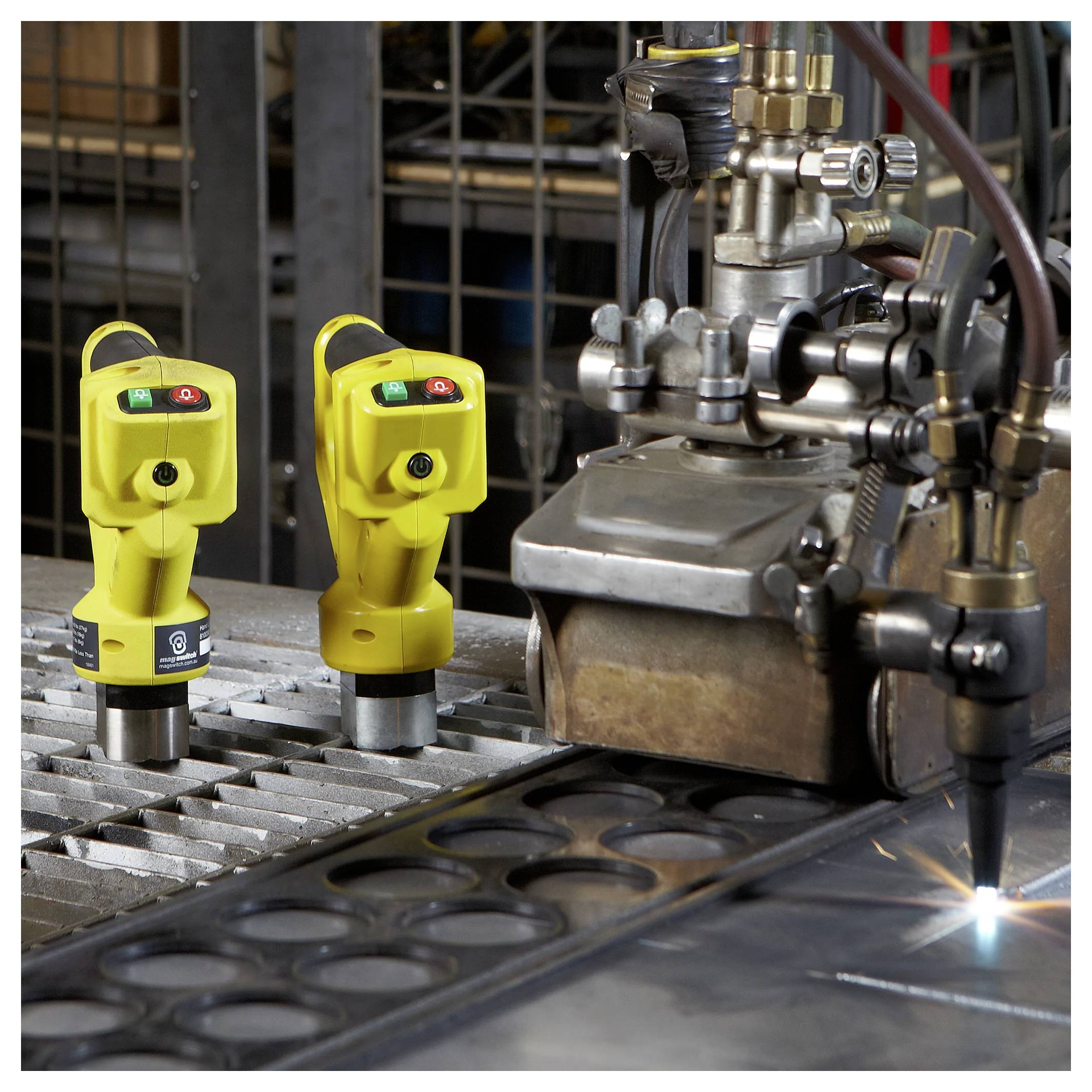 Industrielle Schneidemaschine, die aktiv an Metallblechen arbeitet, mit zwei gelben Sicherheitssensoren in der Nähe zur Überwachung der Arbeitsabläufe.