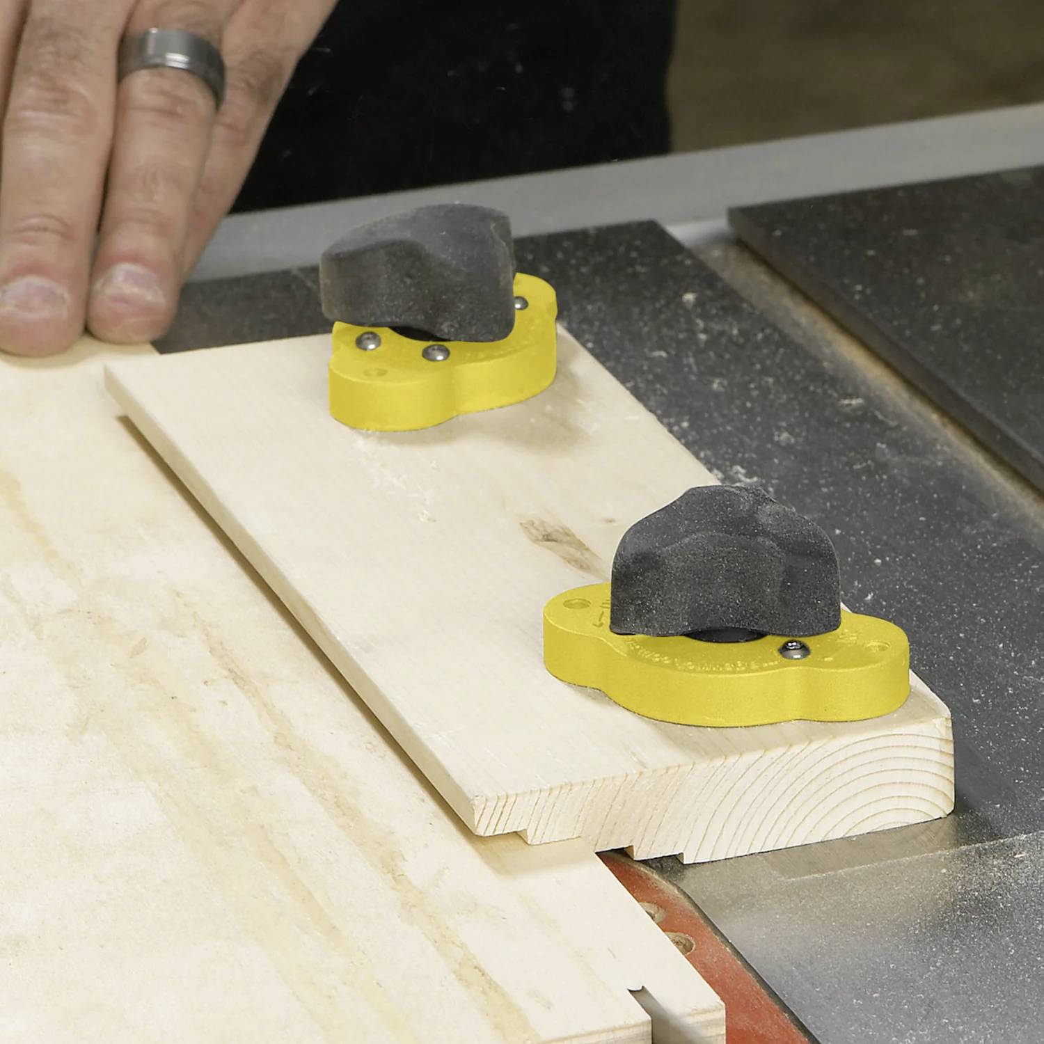 Ein Handwerker verwendet eine Tischkreissäge mit einer Andrückvorrichtung, um Holz für präzise und sichere Schnitte zu führen.