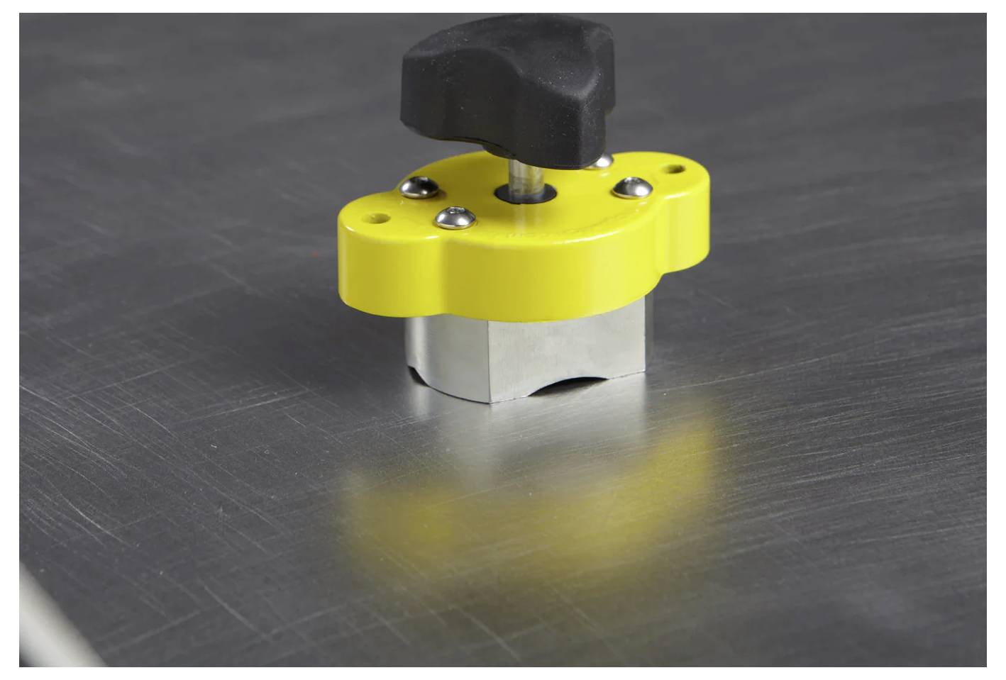 Eine gelbe Metallverriegelung mit einem schwarzen Griff sichert die Oberfläche eines Metallblechs.