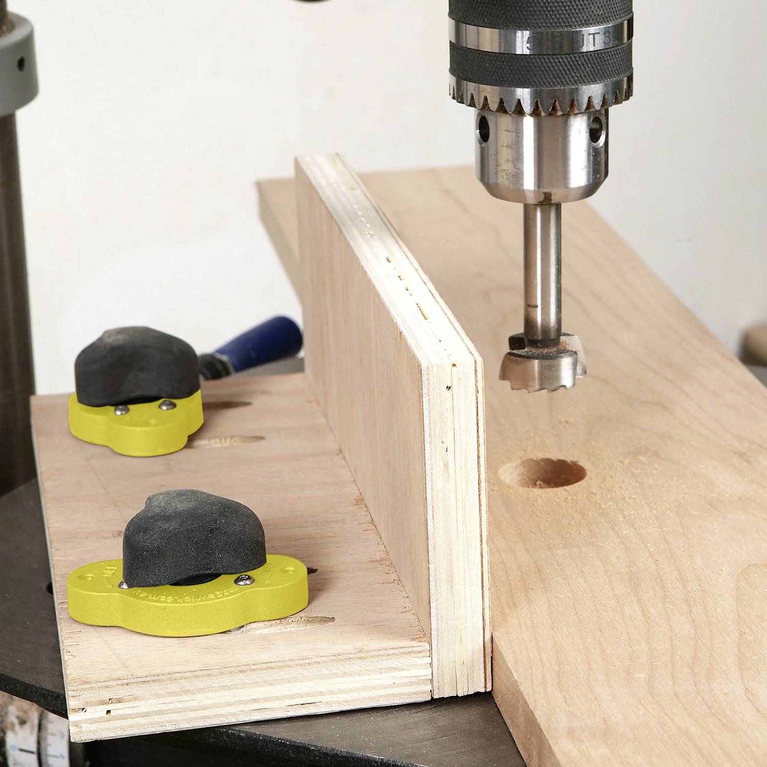 Eine Bohrmaschine bohrt ein Loch in ein Stück Holz, das sicher an einer Werkbank eingespannt ist und damit einen Holzbearbeitungsprozess veranschaulicht.