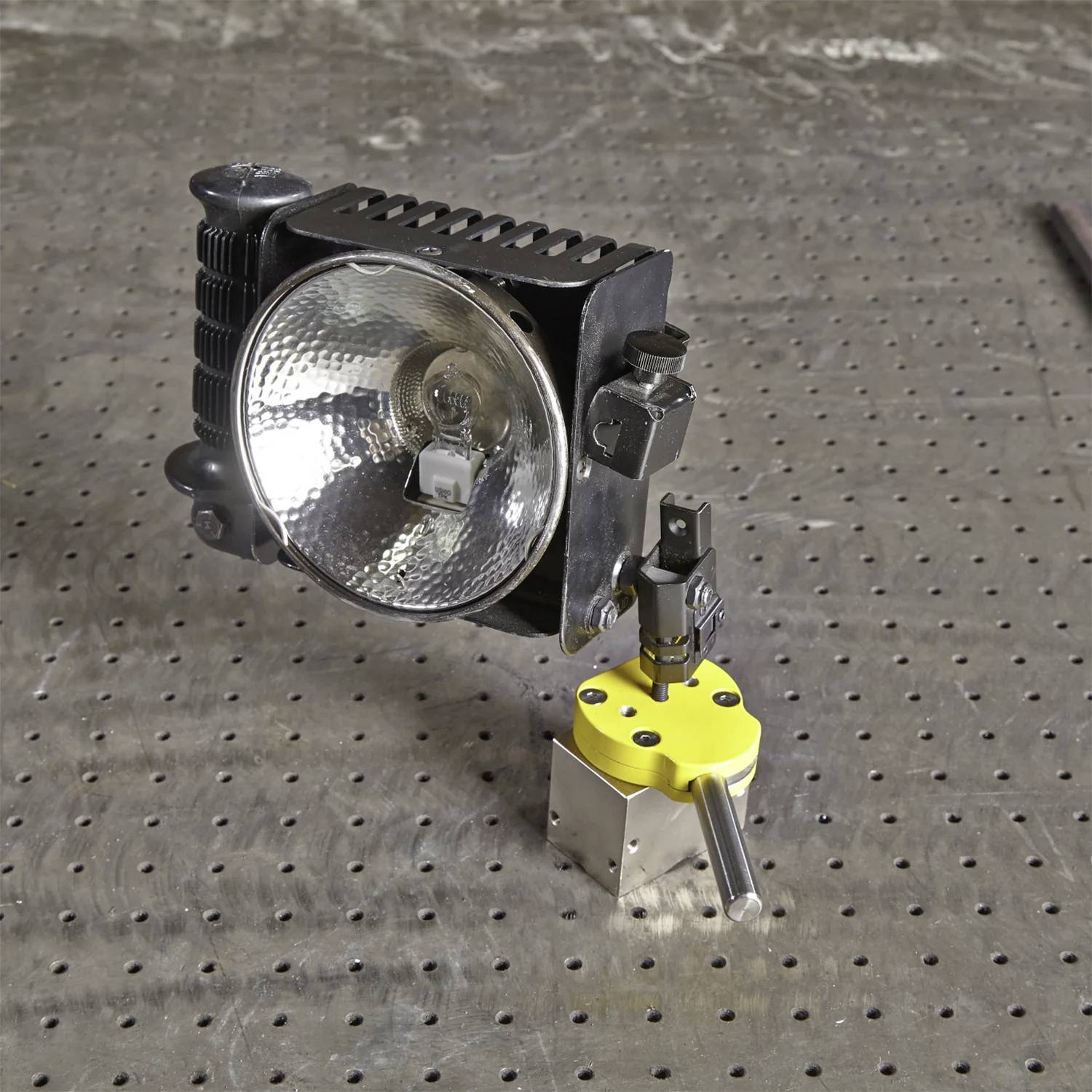 Eine Metallwerkbank verfügt über eine industrielle Leuchte, die sich neben einem Werkzeughalter mit einer sechseckigen gelben Basis befindet und präzisionswerkzeuge ausstellt.