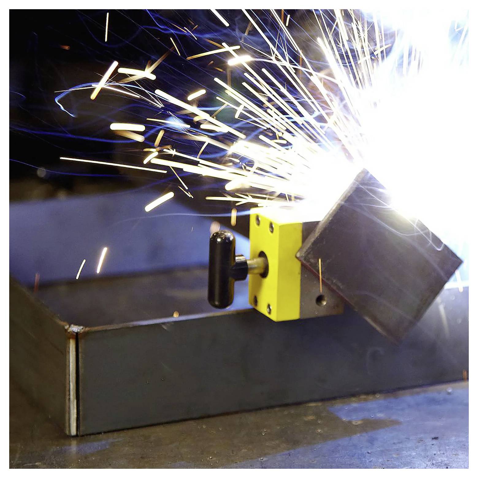 Ein heller Schweißfunke sprüht zwischen zwei Metallstücken, die in einer Werkstattumgebung verbunden werden, und unterstreicht die Intensität des Schweißvorgangs.