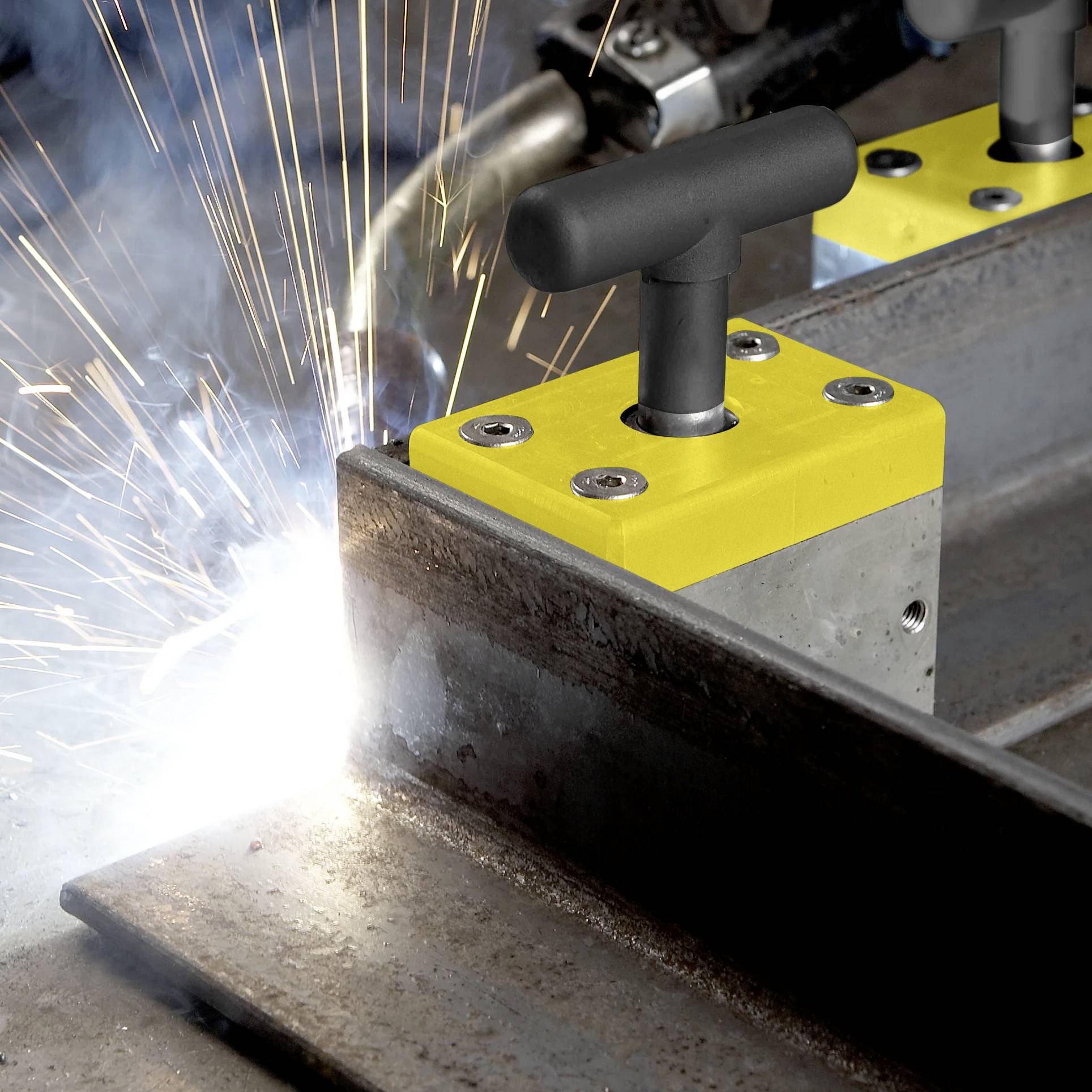 Nahaufnahme eines Schweißers, der eine Magnetklemme verwendet, um Metallteile zusammenzuhalten, während helle Funken sprühen, während der Schweißbrenner angesetzt wird.