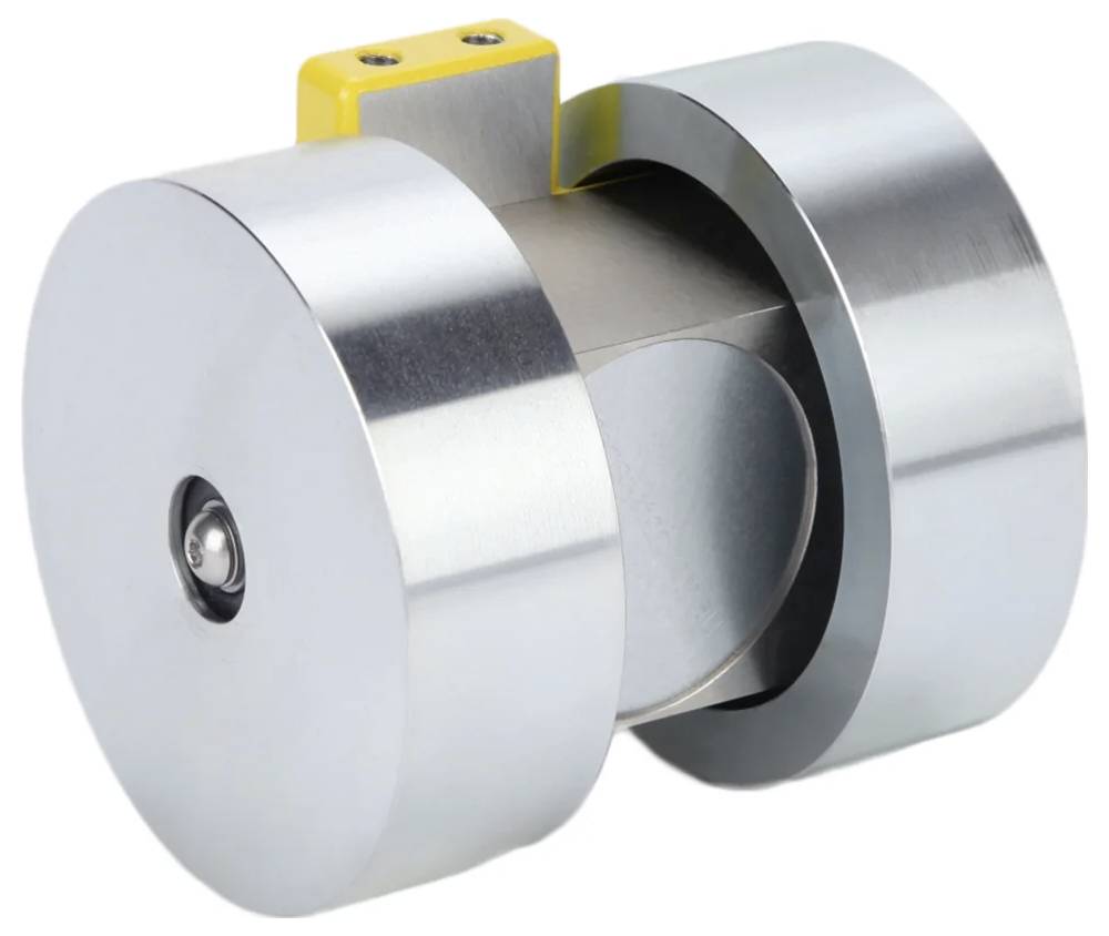 Eine Nahaufnahme eines metallischen zylindrischen Geräts mit einer kleinen gelben Komponente oben drauf. Das Gerät hat glänzende Oberflächen und ein industrielles Design.