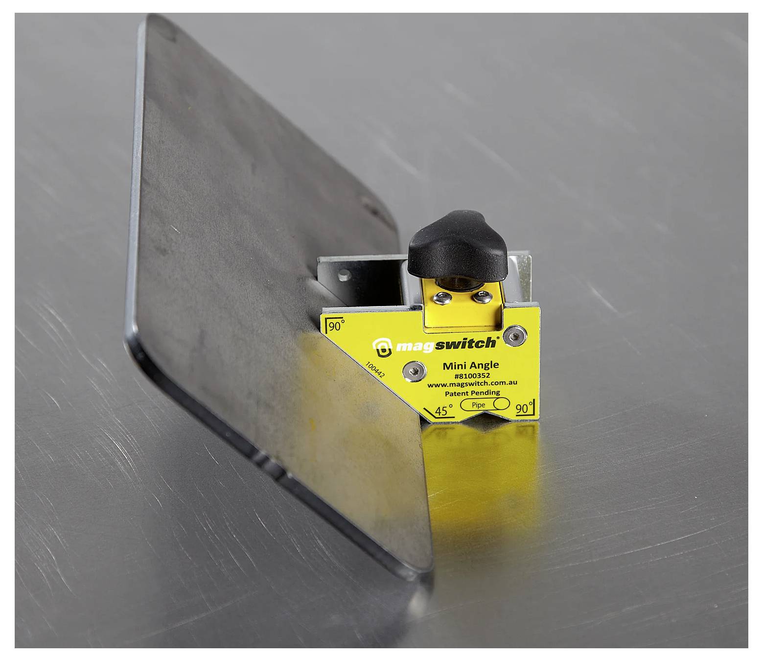 „Ein Magswitch Mini Winkel-Werkzeug, das ein Metallblech in einem 45-Grad-Winkel auf einer metallischen Oberfläche hält und magnetische Unterstützung für Schweiß- oder Positionierungsaufgaben veranschaulicht.
