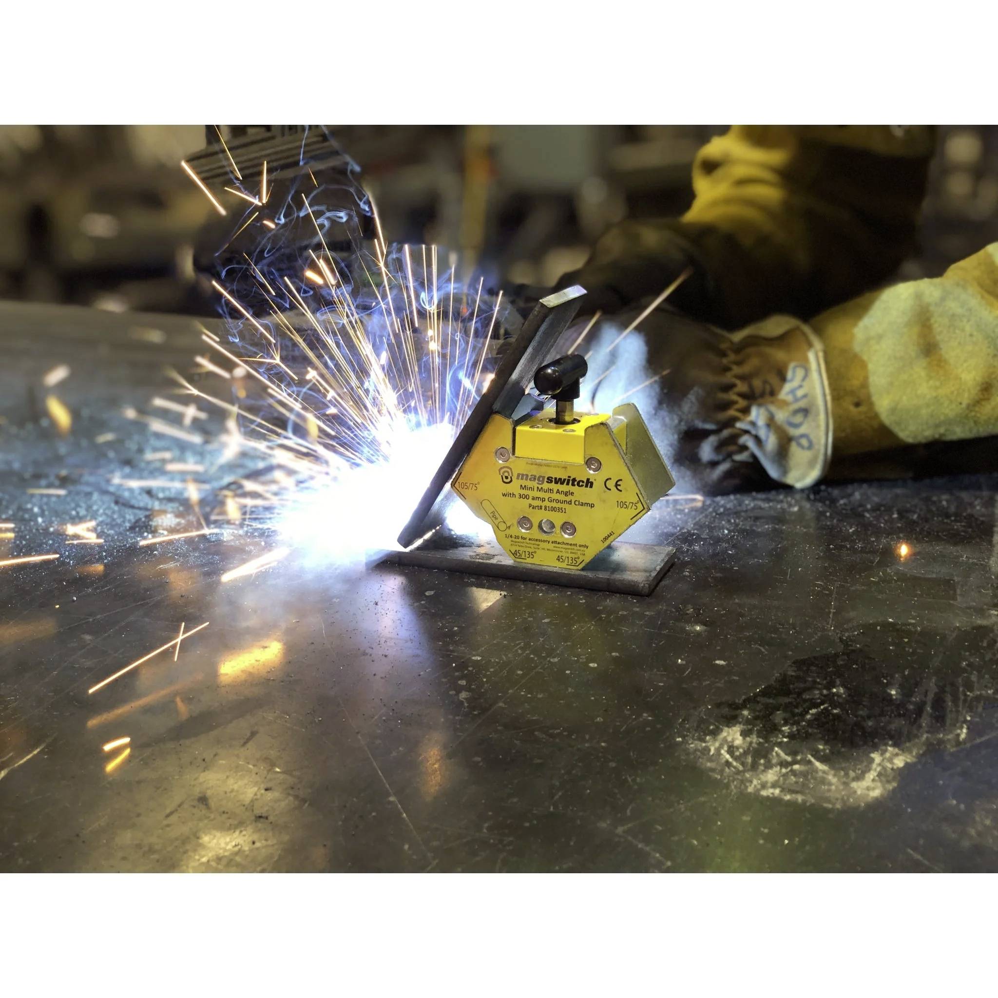 Eine Person mit Schutzhandschuhen führt ein Schweißwerkzeug und erzeugt helle Funken auf einer Metalloberfläche in einer industriellen Umgebung.