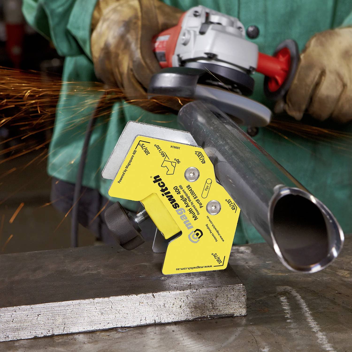 Eine Person verwendet eine Winkelschleifer, um ein Metallrohr zu schneiden, wobei Funken umherfliegen. In der Nähe befindet sich eine gelbe magnetische Stütze mit der Aufschrift „Magswitch Welding