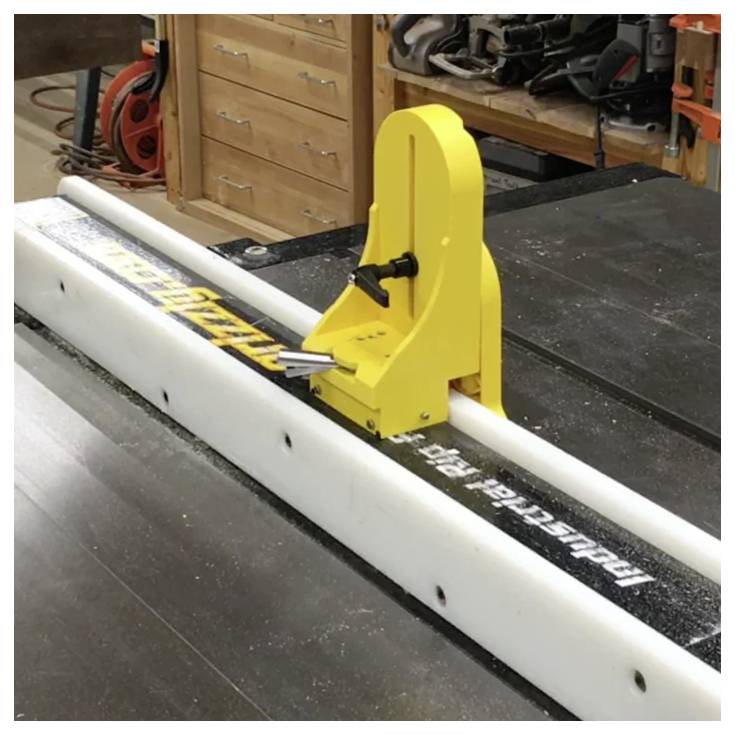 Eine gelbe Tischkreissäge-Führungshilfe an einer Säge mit einer weißen Führungsschiene, verwendet für präzise Schnitte in der Holzbearbeitung. Werkstattgeräte sind im Hintergrund sichtbar.