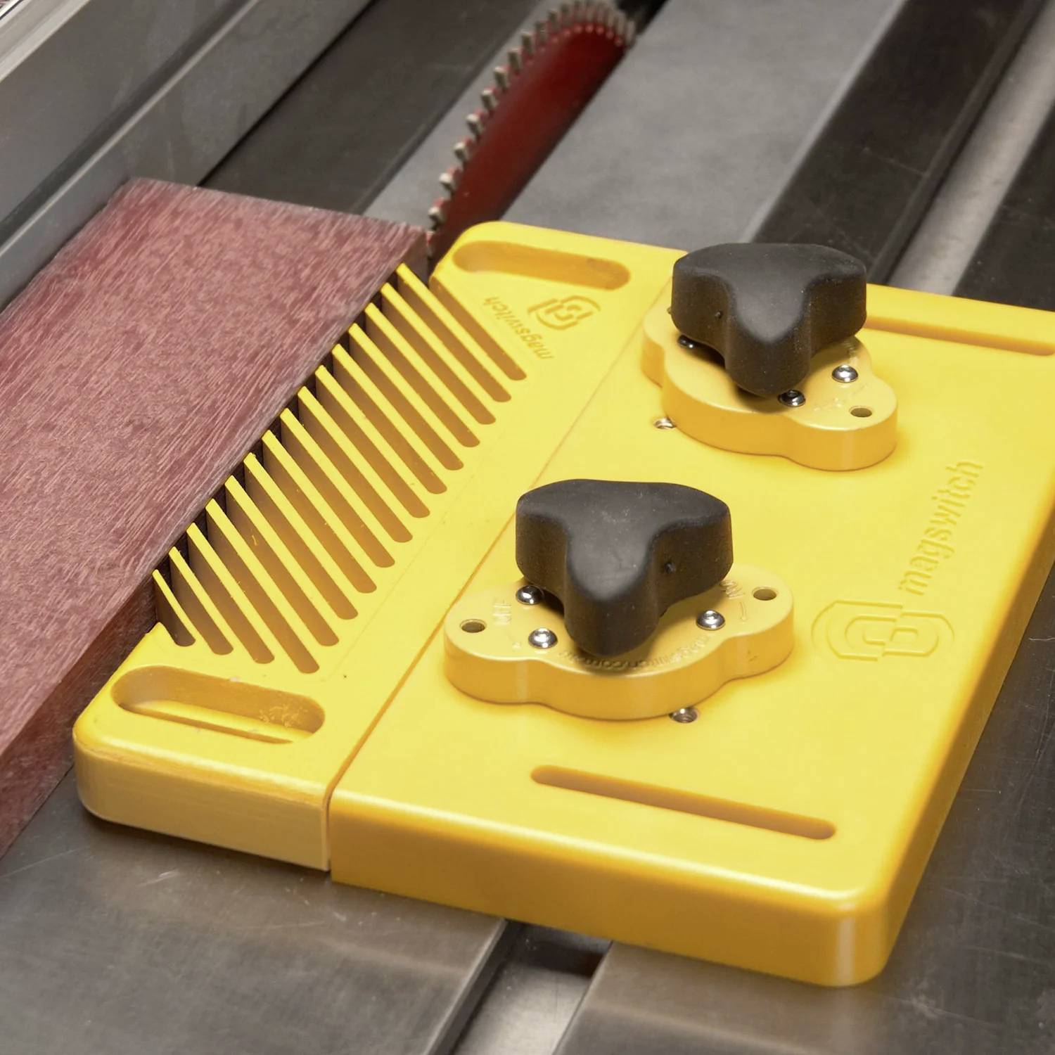 Ein gelbes Sicherheitswerkzeug mit Knöpfen und einer kammartige Konstruktion ist an einer Kreissäge befestigt und führt Holz für präzises und sicheres Sägen.