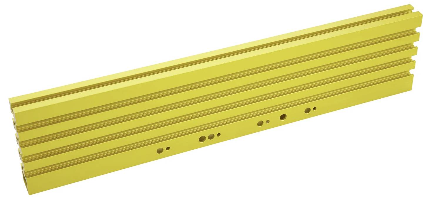 Eine lange, gelbe Metallschiene mit mehreren Löchern und Rillen, wahrscheinlich Teil eines Bau- oder Montagessystems, auf einem weißen Hintergrund platziert.