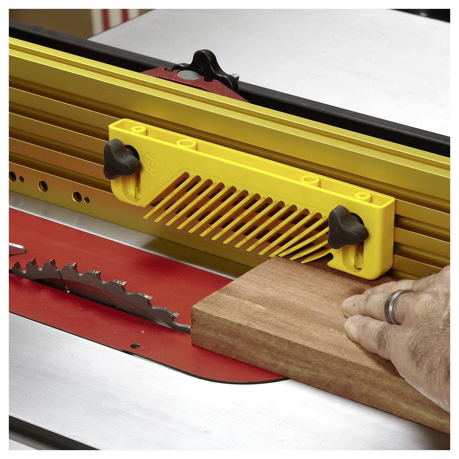 Eine Hand führt ein Holzstück durch eine Kreissäge und verwendet dabei eine gelbe Sicherheitsführung, um Präzision und Sicherheit beim Schneiden zu gewährleisten.