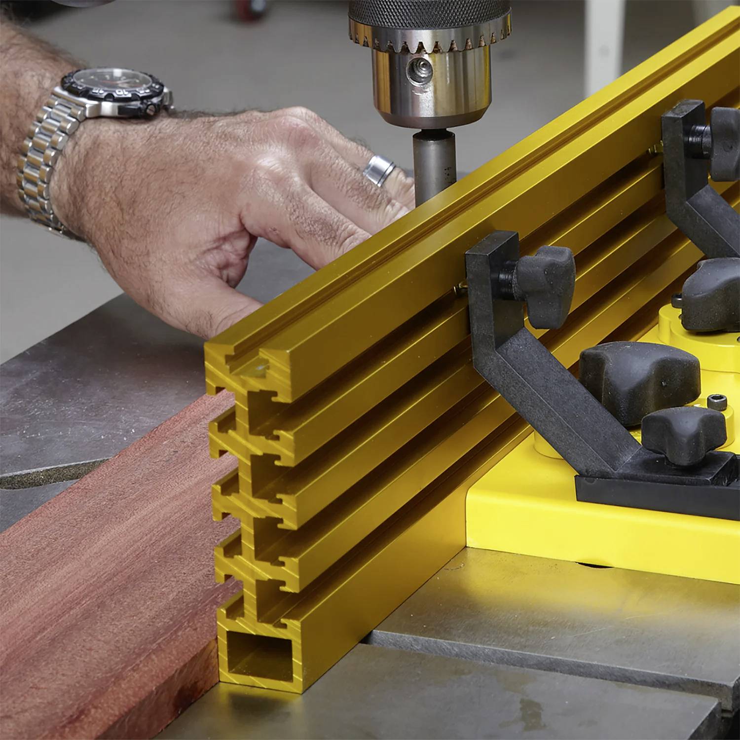Eine Person justiert eine Metallführung an einer Tischkreissäge und richtet ein Holzstück für einen präzisen Schnitt aus.