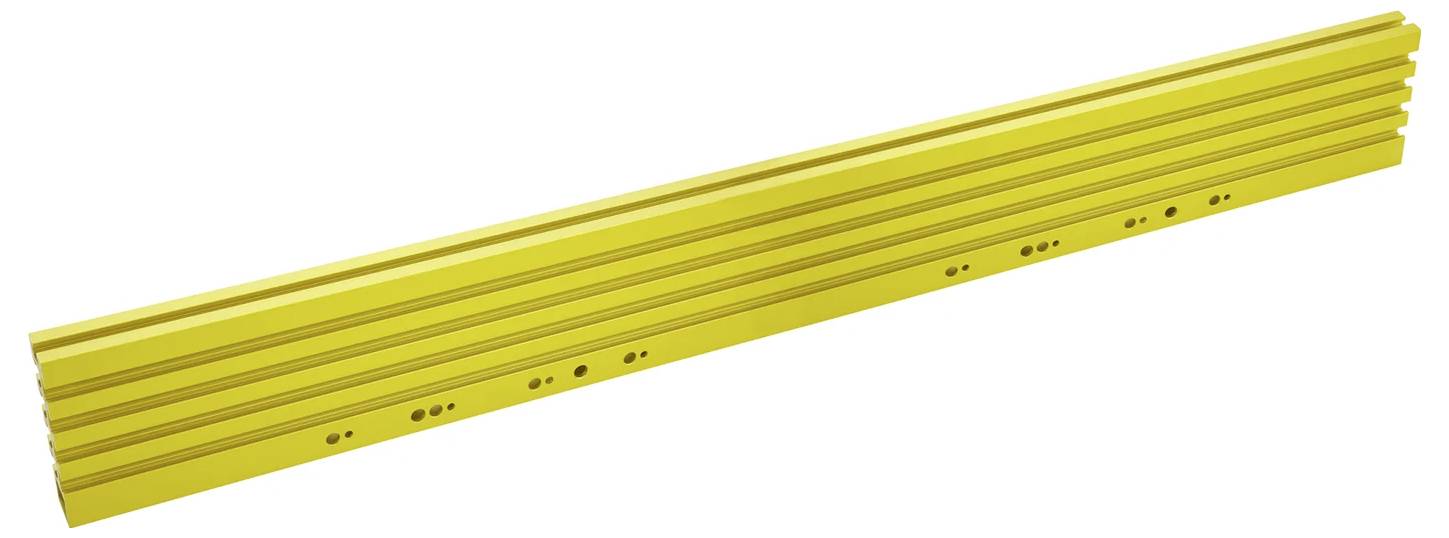 Eine lange, gelbe T-Nutenschiene mit mehreren Löchern, die wahrscheinlich für Montage- oder Zusammenbauanwendungen in Werkstätten oder Fertigungsumgebungen verwendet wird.