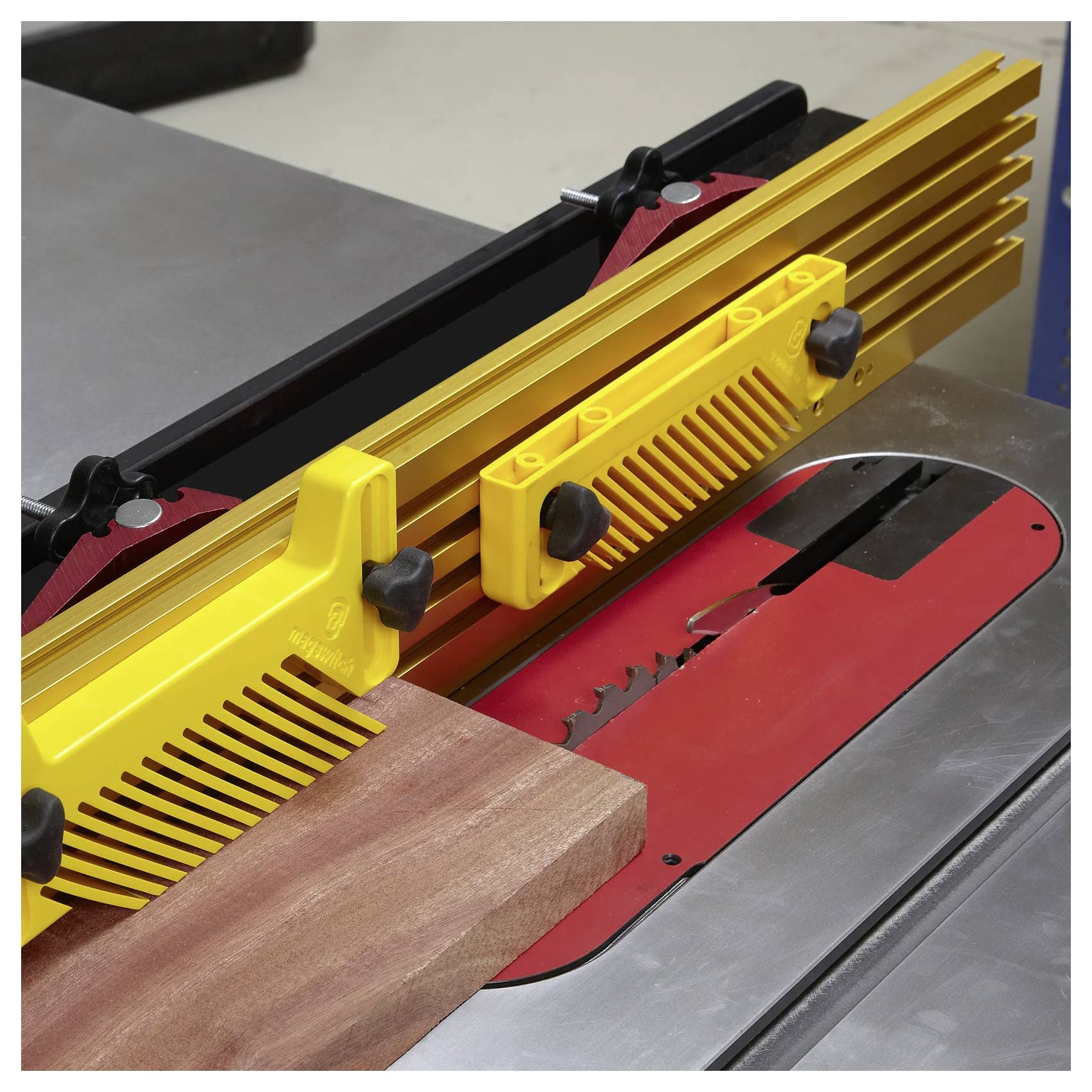 Eine Tischkreissäge, die ein Holzbrett zersägt; ein gelber Andrückhalter gewährleistet Stabilität und Präzision und verbessert so die Sicherheit und Genauigkeit während des Vorgangs.