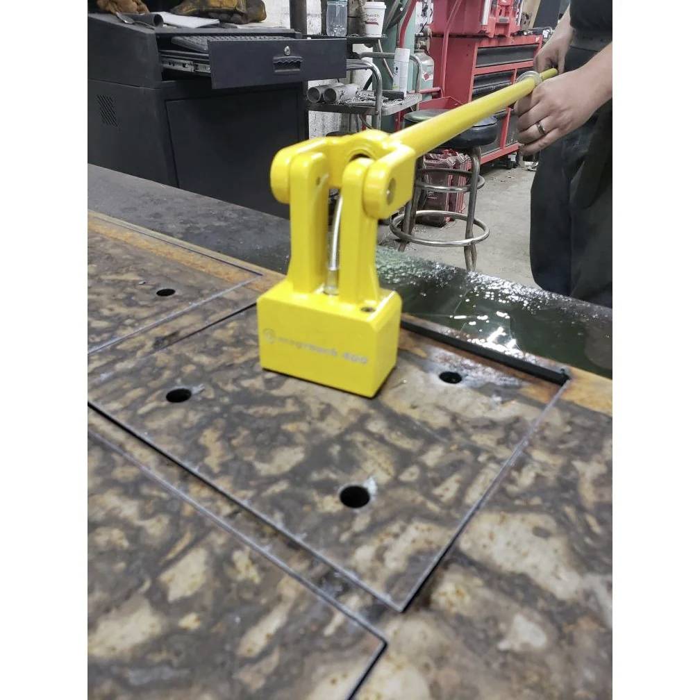 Eine Person bedient ein gelbes Magnethebewerk des Typs Magnetic 400, um ein Metallblech in einer Werkstattumgebung zu handhaben.