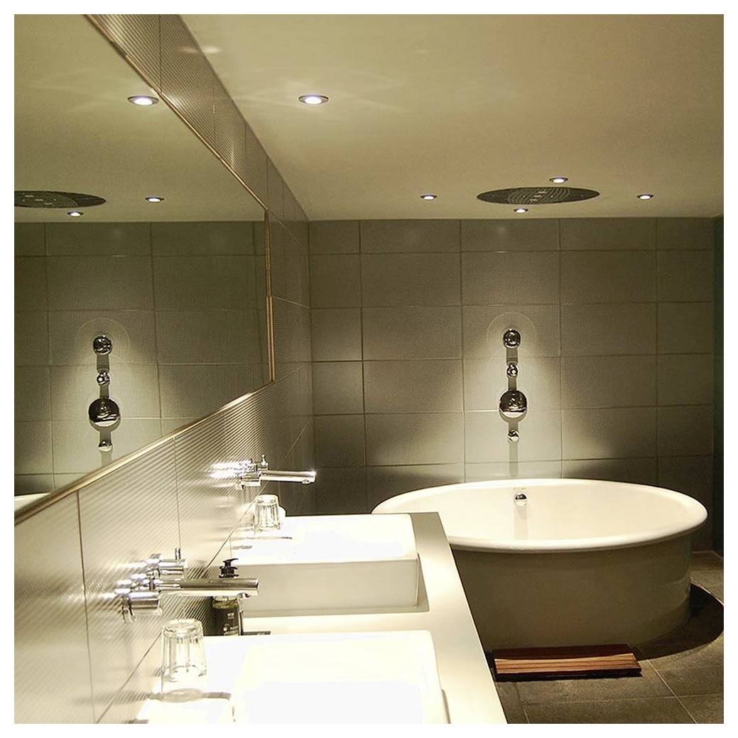 Modernes Badezimmer mit einer runden Badewanne, Doppelwaschbecken auf einer Arbeitsplatte, großem Spiegel, gefliesten Wänden und Deckenbeleuchtung.