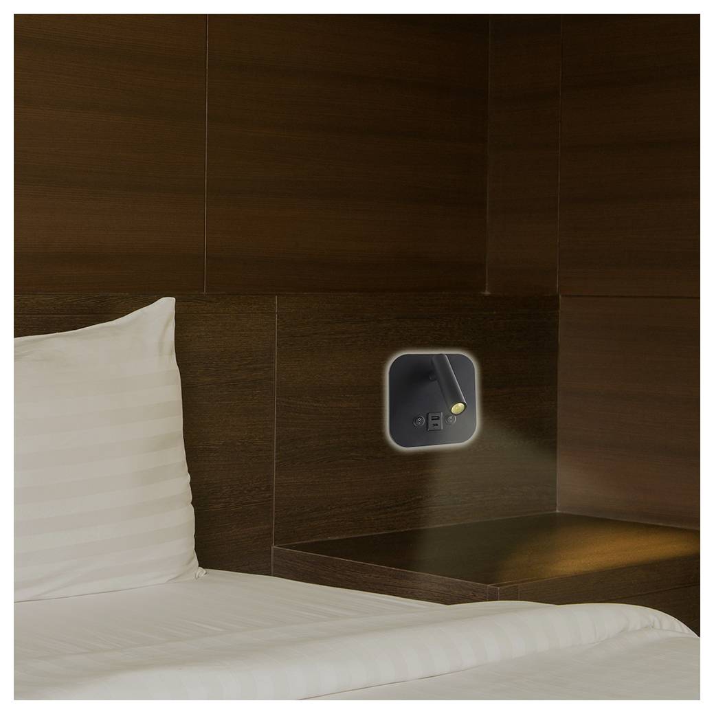 Ein ordentlich gemachtes Bett mit weißen Laken steht neben einer dunklen Holzvertäfelung, die über dem Kopfteil eine eingebaute Leselampe aufweist.