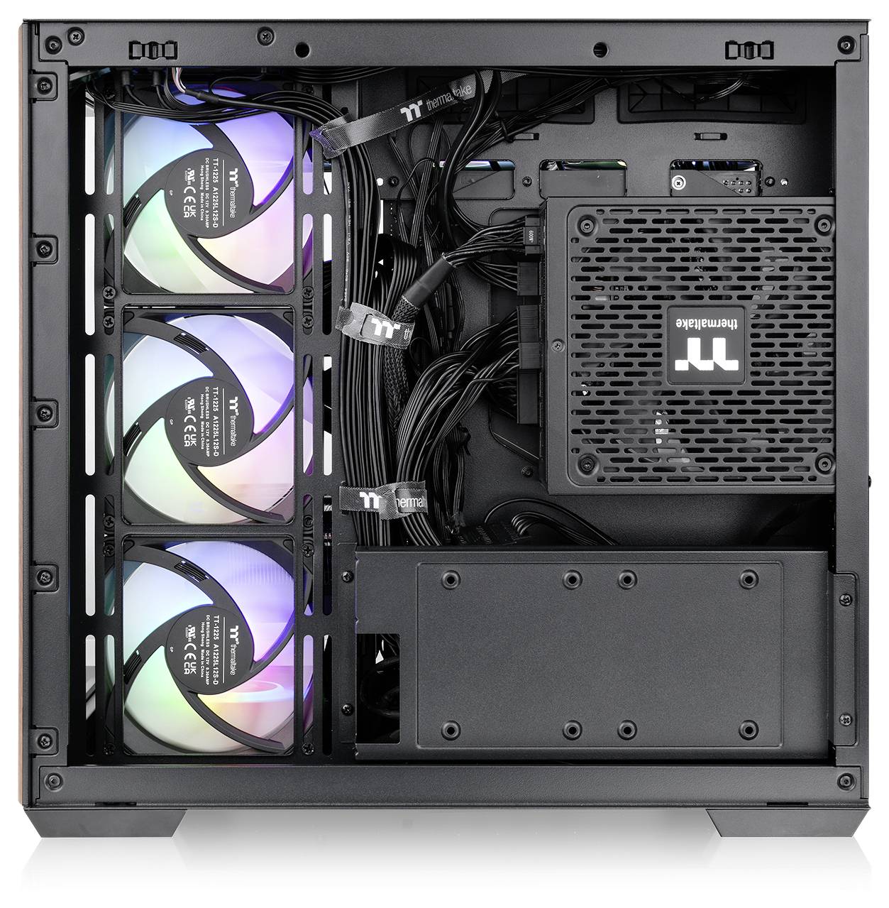 Das Innere eines Computergehäuses mit drei RGB-Lüftern auf der linken Seite, einem mit 'Thermaltake' beschrifteten Netzteil auf der rechten Seite und sorgfältig verlegten Kabeln.