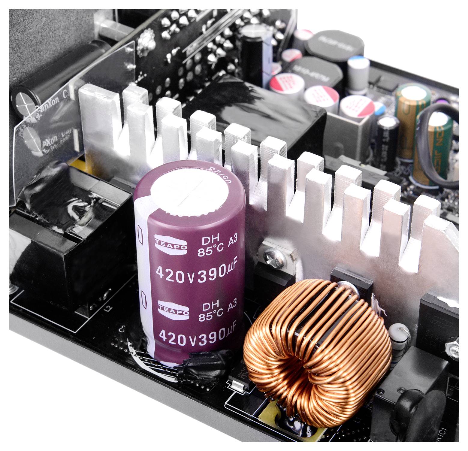 Nahaufnahme einer Computer-Netzteilplatine mit einem großen Kondensator, der mit '420V 390μF' gekennzeichnet ist, einem Kühlkörper und einer Kupferspule.