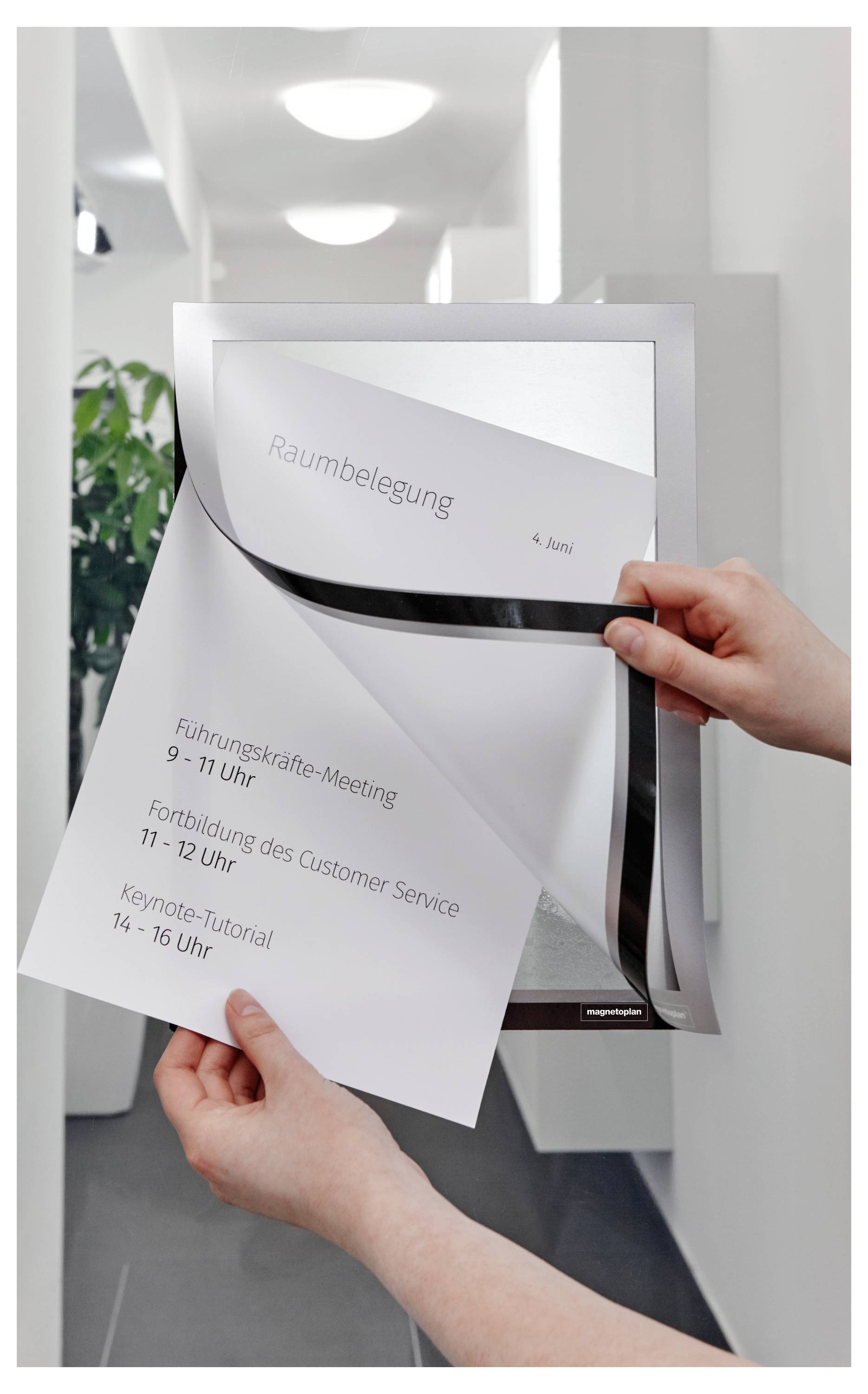 Eine Person ändert einen Zeitplan an einer Wandanzeige für die Raumbelegung am 4. Juni und trägt Meetings und Tutorien mit Zeiten und Themen ein.