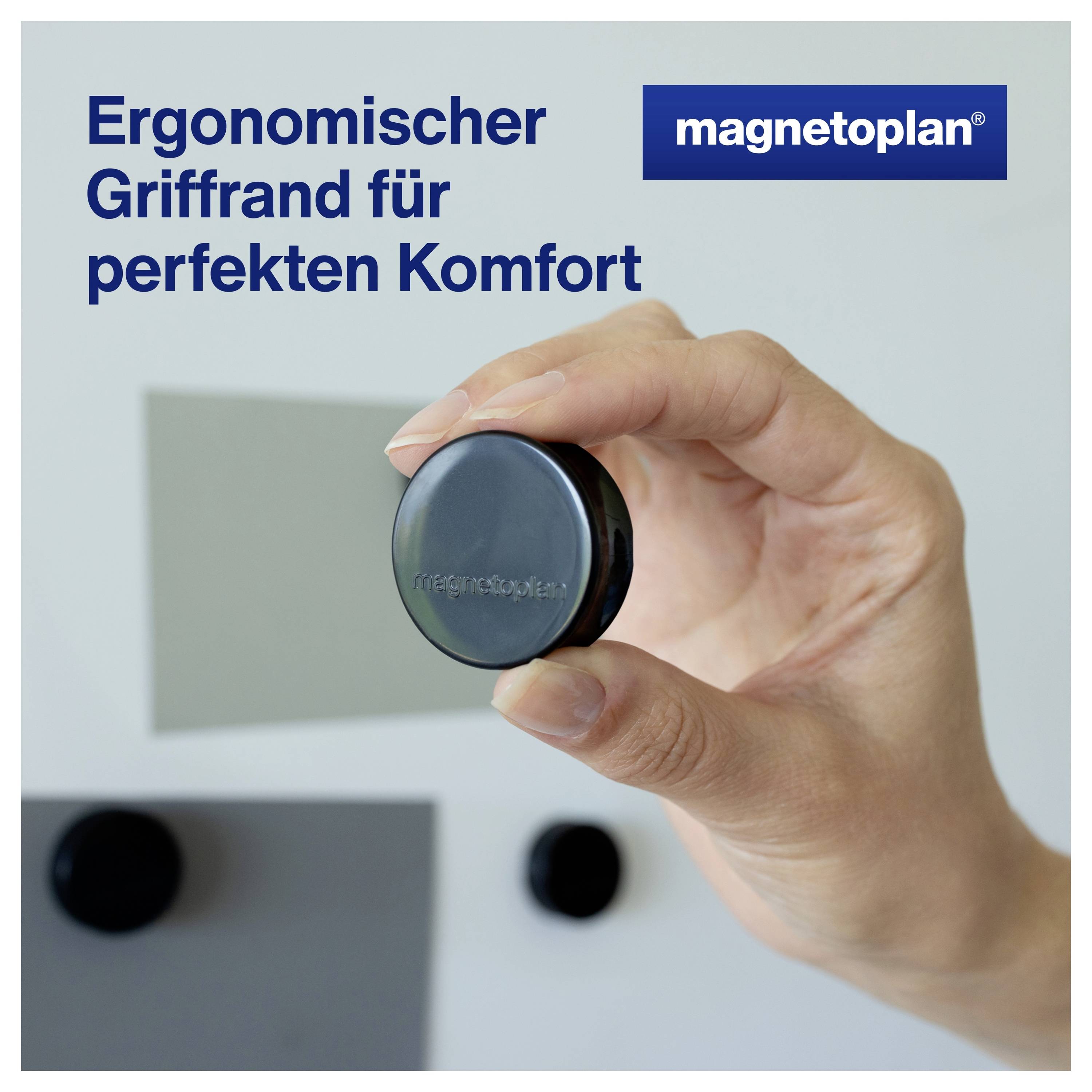 Eine Hand hält ein rundes magnetisches Bretterzubehör mit dem Text 'Ergonomischer Griffrand für perfekten Komfort' und 'magnetoplan'.