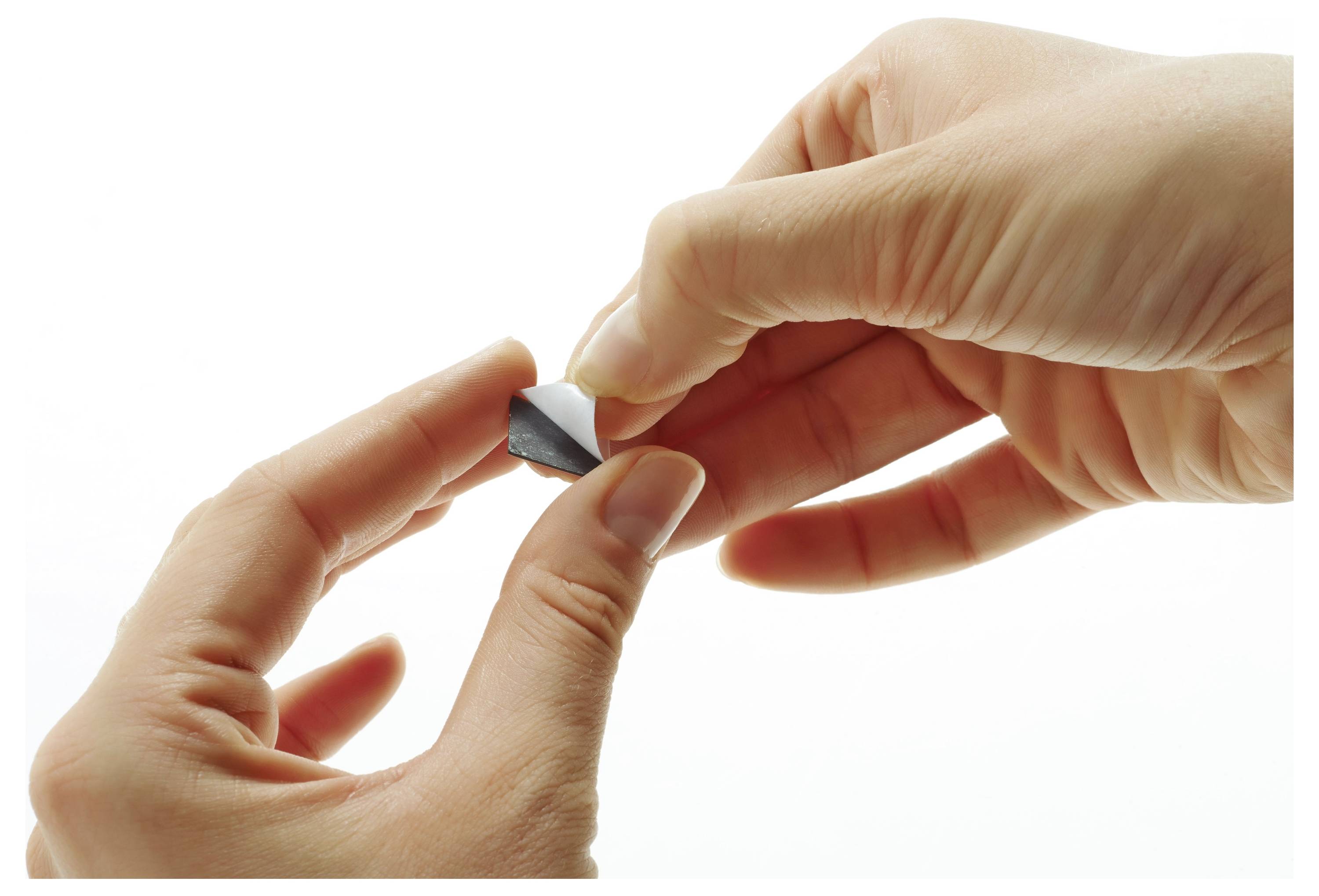 Zwei Hände, die ein kleines Stück dunklen Stoff vor einem einfarbigen weißen Hintergrund falten.