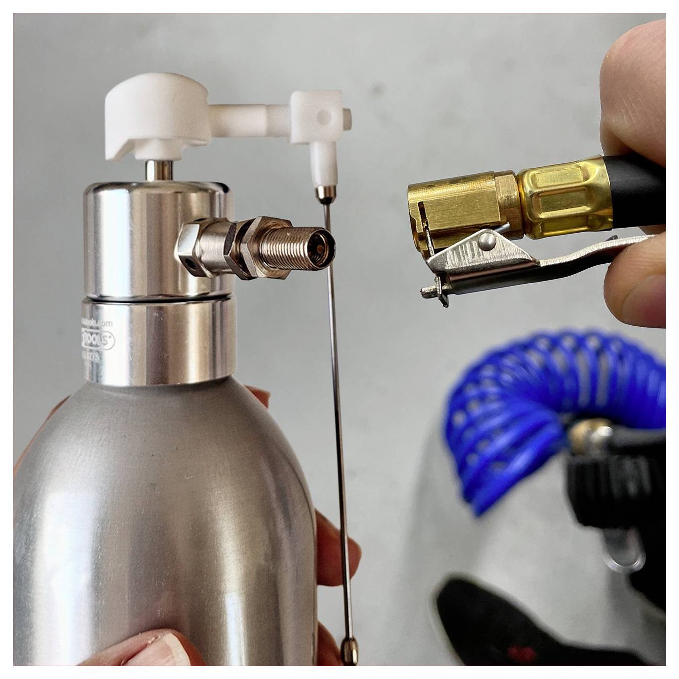Eine Person, die eine Luftdüsenkanone unter Verwendung eines Metallbehälters und eines Schlauchs mit Messingarmatur zusammenbaut und diese für den Einsatz vorbereitet.