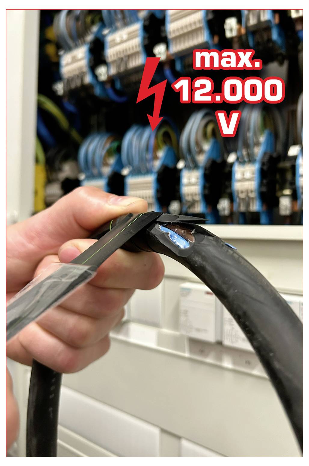 Eine Person, die ein dickes schwarzes Kabel vor einem Elektroschrank mit einem Warnschild handhabt, auf dem ‚max. 12.000 V' steht.