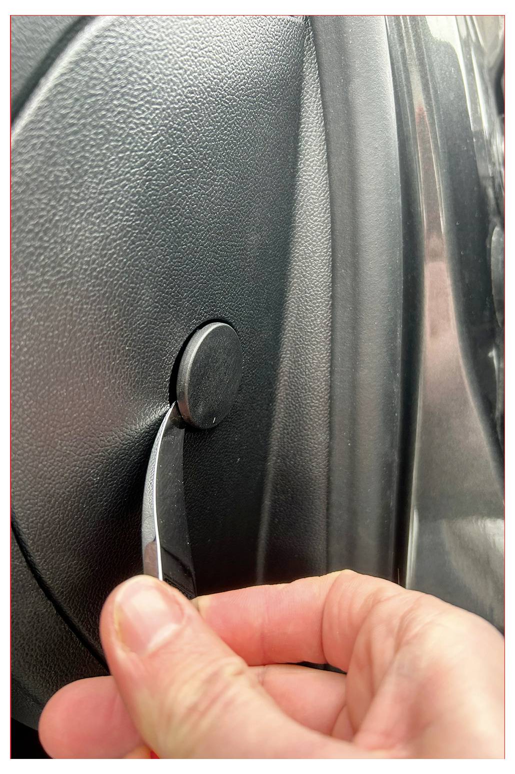 Hand zieht einen kreisförmigen Türöffnungshebel, was eine manuelle Entriegelungsaktion an einer Fahrzeugtür andeutet.