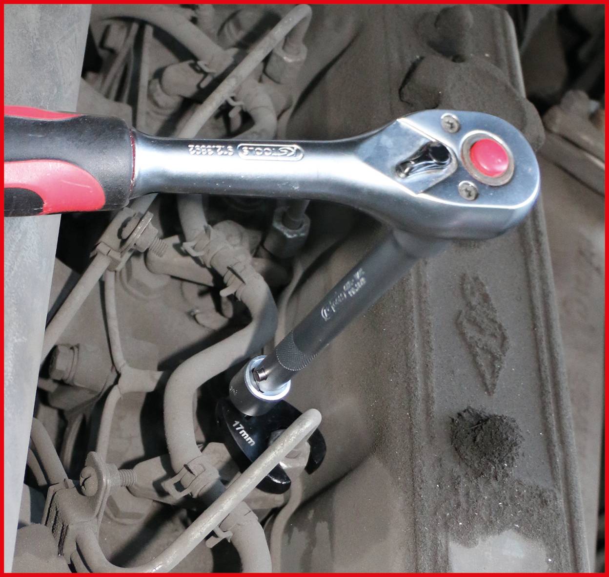 Ein Ratschenschlüssel, der einen Bolzen an einem Automotor festzieht und mechanische Wartung demonstriert.