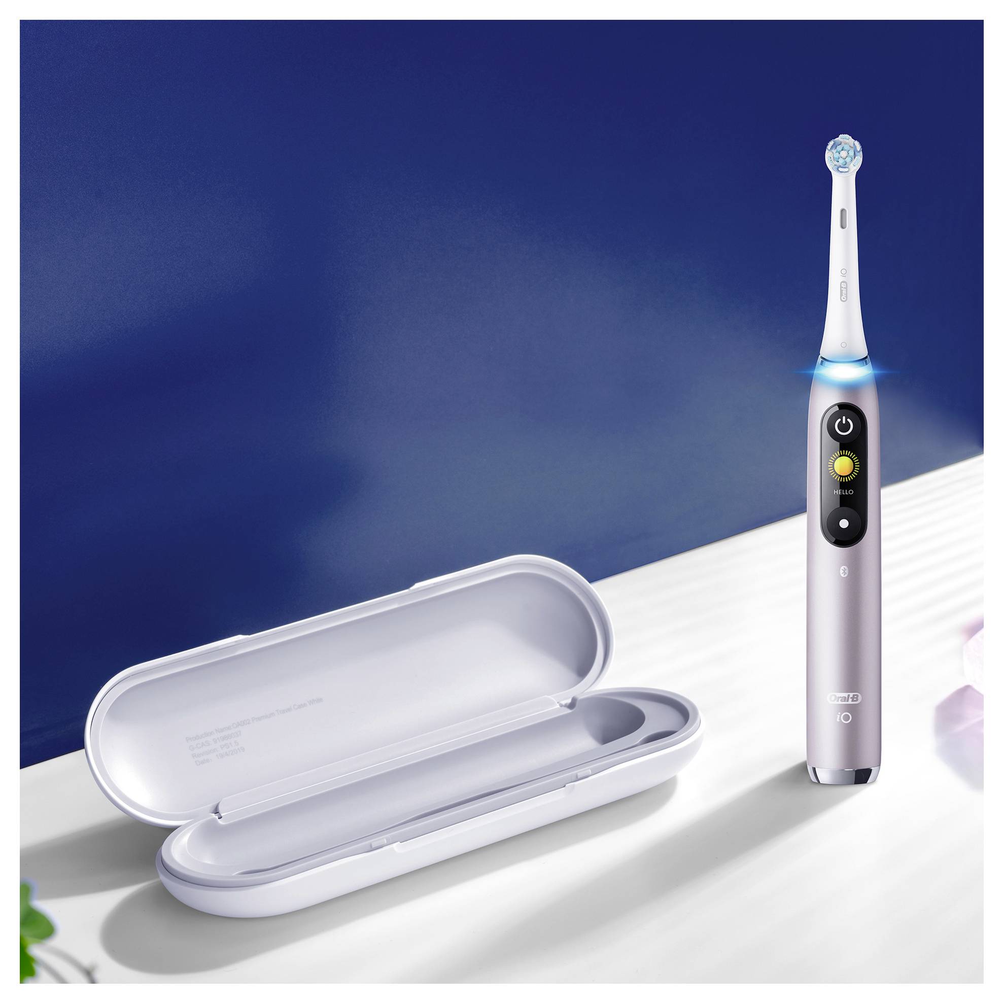 Eine elektrische Zahnbürste steht aufrecht neben einem geöffneten Transportetui auf einer weißen Arbeitsfläche unter einer dunkelblau gestrichenen Wand.