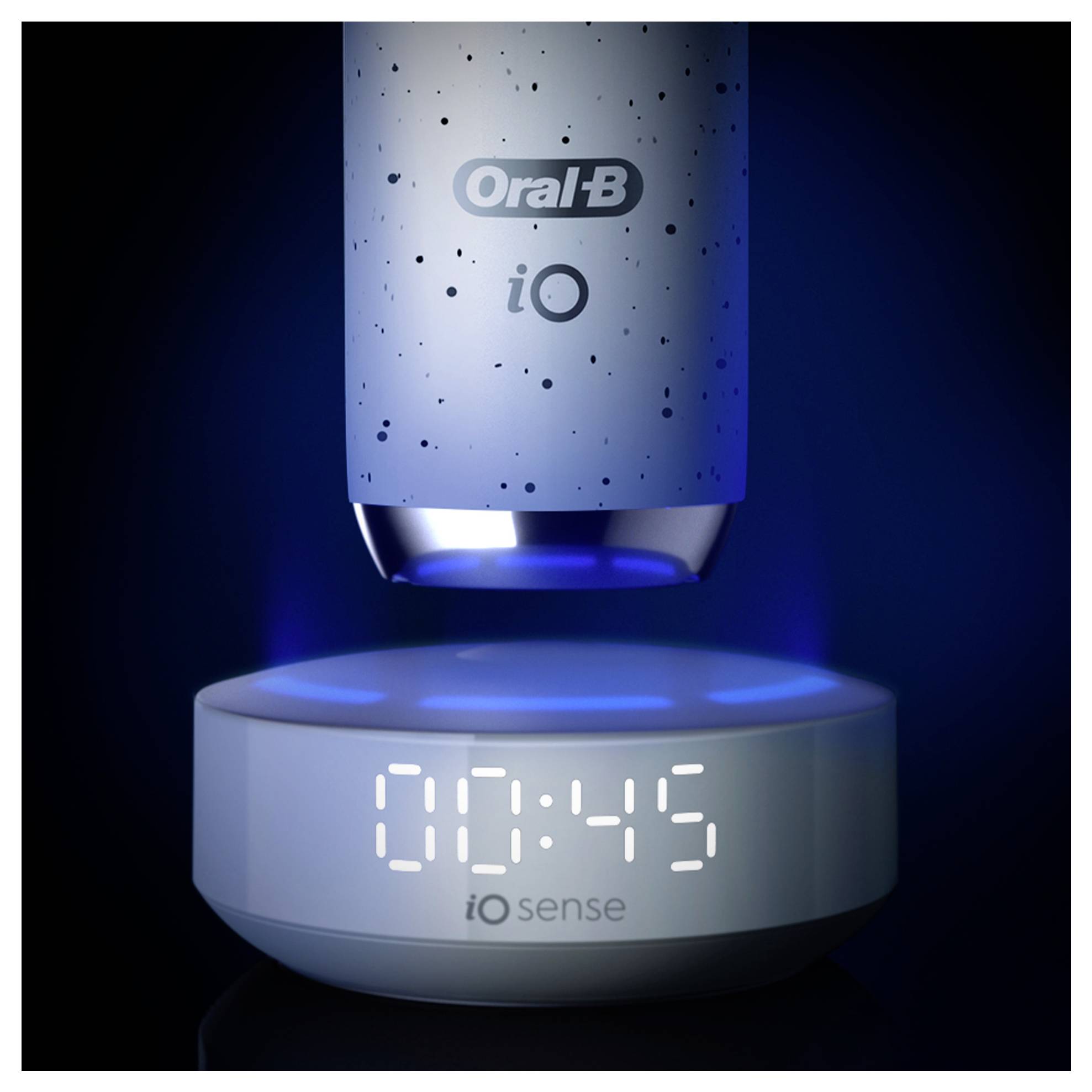 Elektrische Zahnbürste über einer Ladestation, die '00:45' mit blauer Beleuchtung anzeigt; markiert mit 'Oral-B iO' und 'iO Sense'.