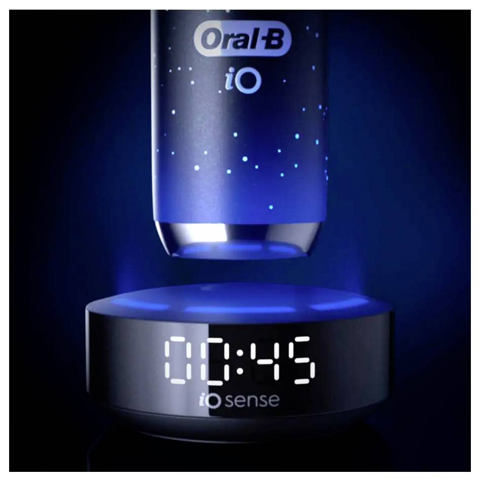 Eine Oral-B iO Elektrozahnbürste, die über einer Ladestation schwebt, mit der Anzeige '10:45' auf der digitalen Uhr der Station, umgeben von einem blauen Leuchten.