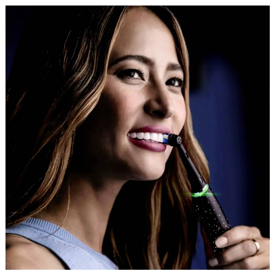 Eine Person lächelt, während sie eine elektrische Zahnbürste benutzt und dabei Zahnhygiene und Mundpflege hervorhebt.