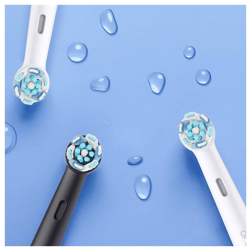 Elektrische Zahnbürstenköpfe in Schwarz und Weiß auf blauem Hintergrund mit Wassertropfen, die Borstentextur und -design zeigen.