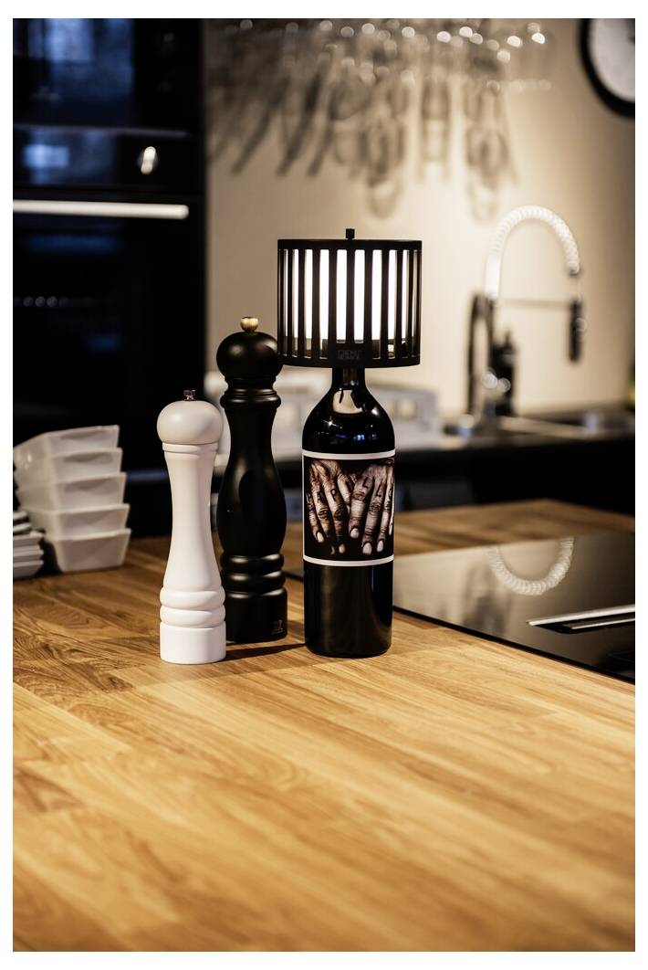 „Holz-Küchenküchenarbeitsplatte mit einer dekorativen Leuchte, die aus einer Weinflasche gefertigt ist, neben einer weiß-schwarzen Pfeffermühle.