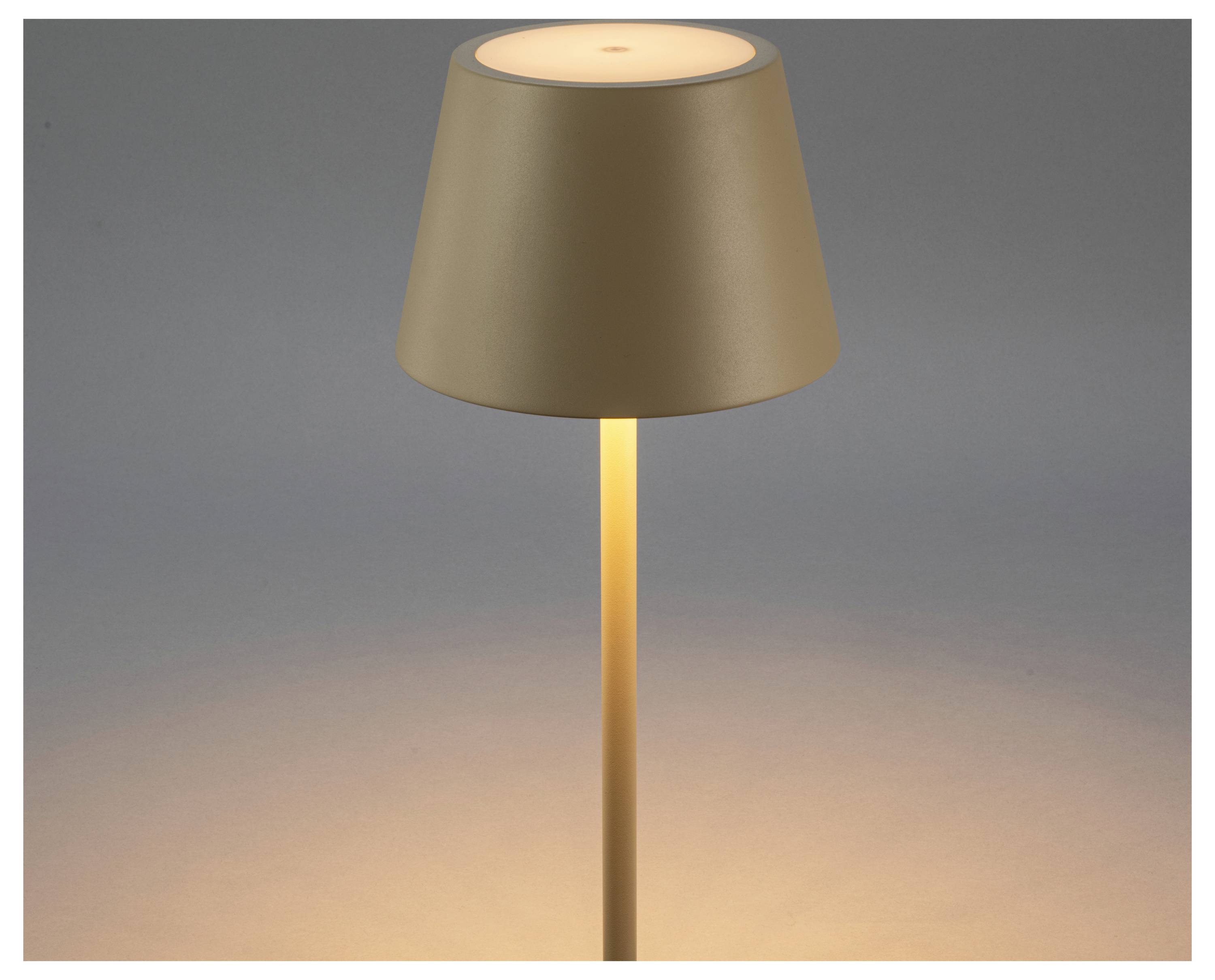 Eine moderne Lampe mit einem beigen Lampenschirm verbreitet warmes Licht und steht in einer minimalistischen Umgebung.