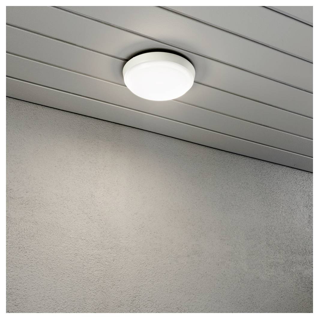 Eine weiße, kreisförmige Deckenleuchte ist an einer grauen Vertäfelung befestigt und verbreitet ein sanftes Licht in der Ecke eines modernen Raumes.