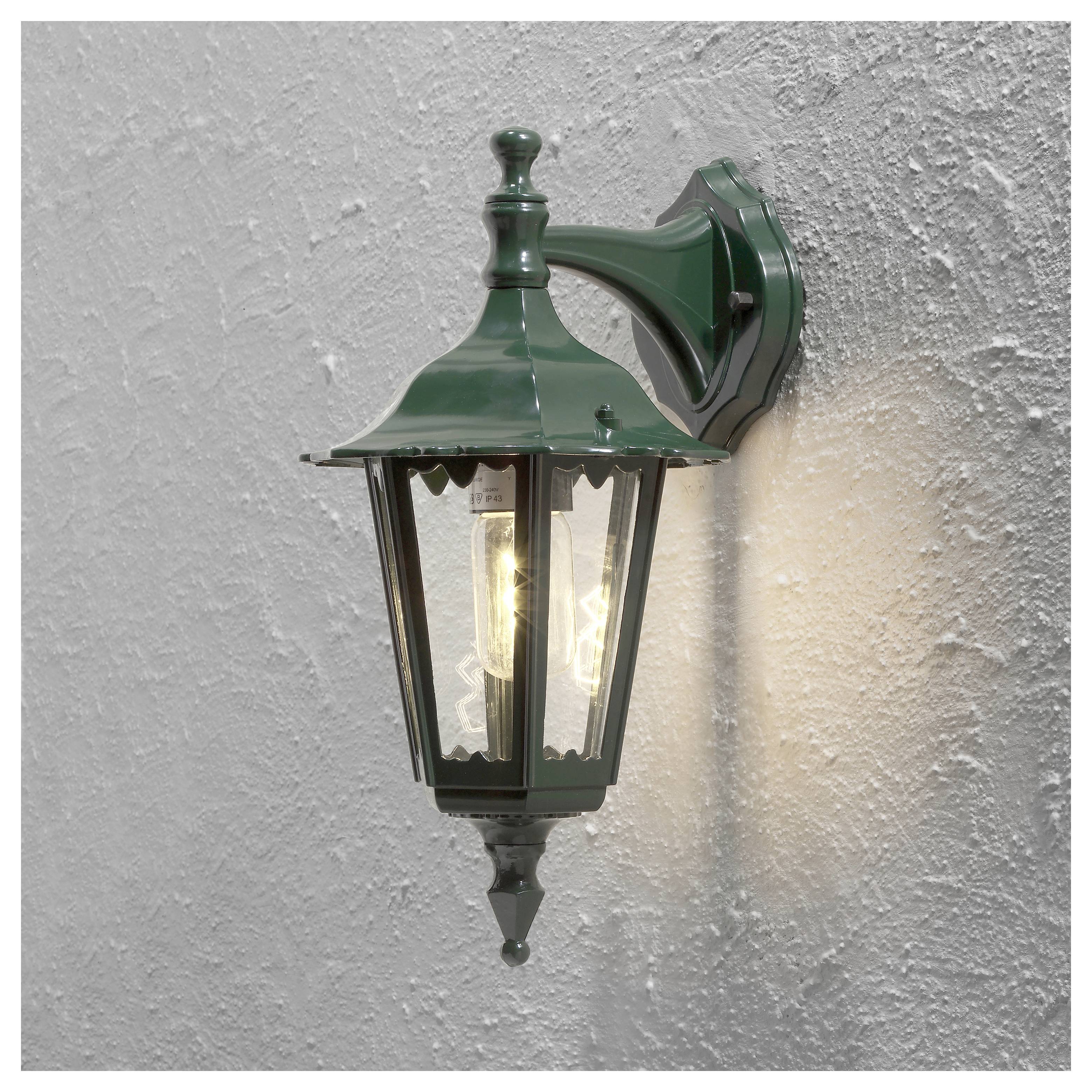 Grüne Metall-Außenwandlampe mit einer leuchtenden Glühbirne, montiert an einer strukturierten weißen Wand.