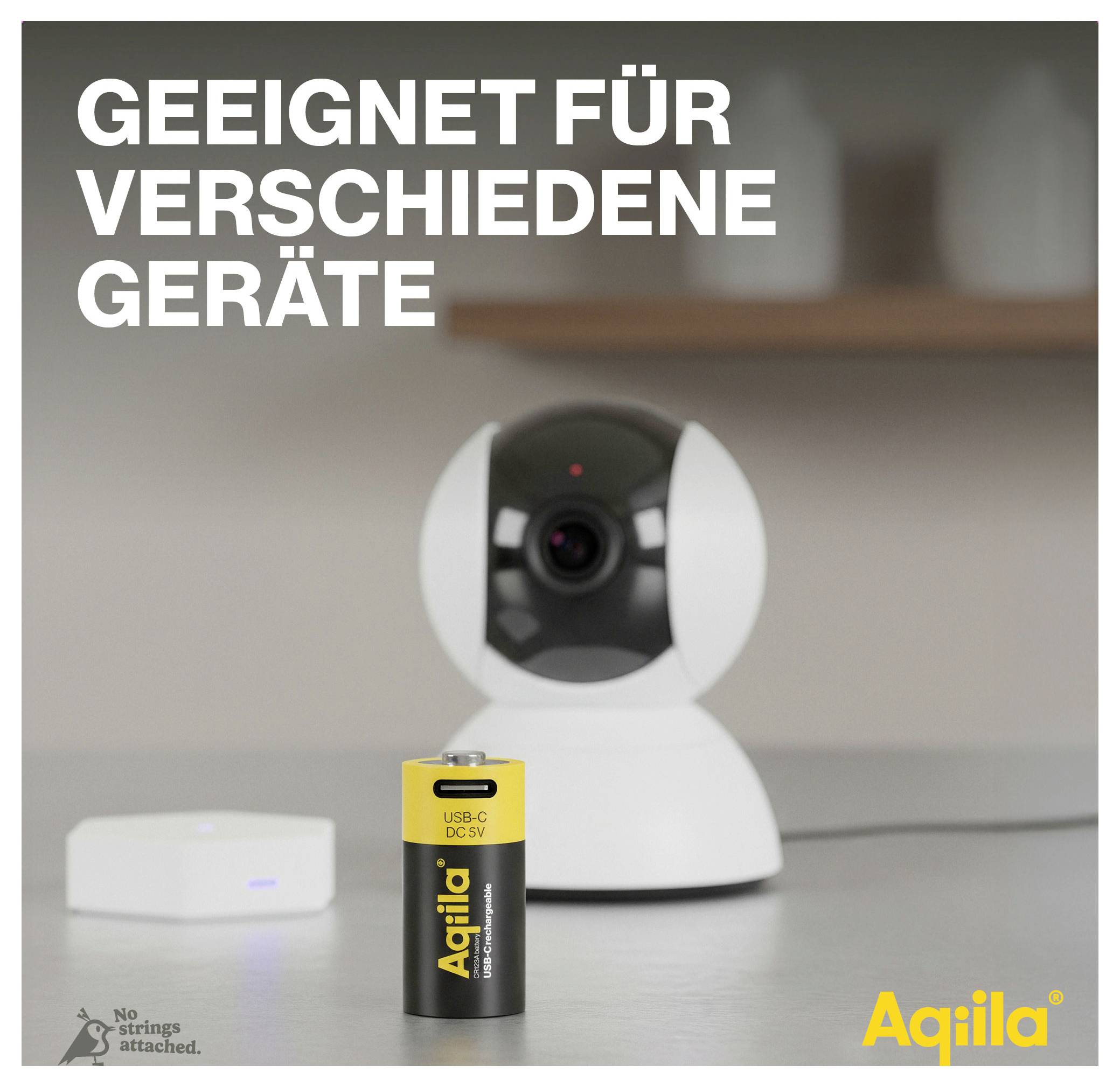 Überwachungskamera und Batterie von 'Aqila' auf Tisch. Text: 'Geeignet für verschiedene Geräte'. Im Hintergrund unscharfes Gerät.